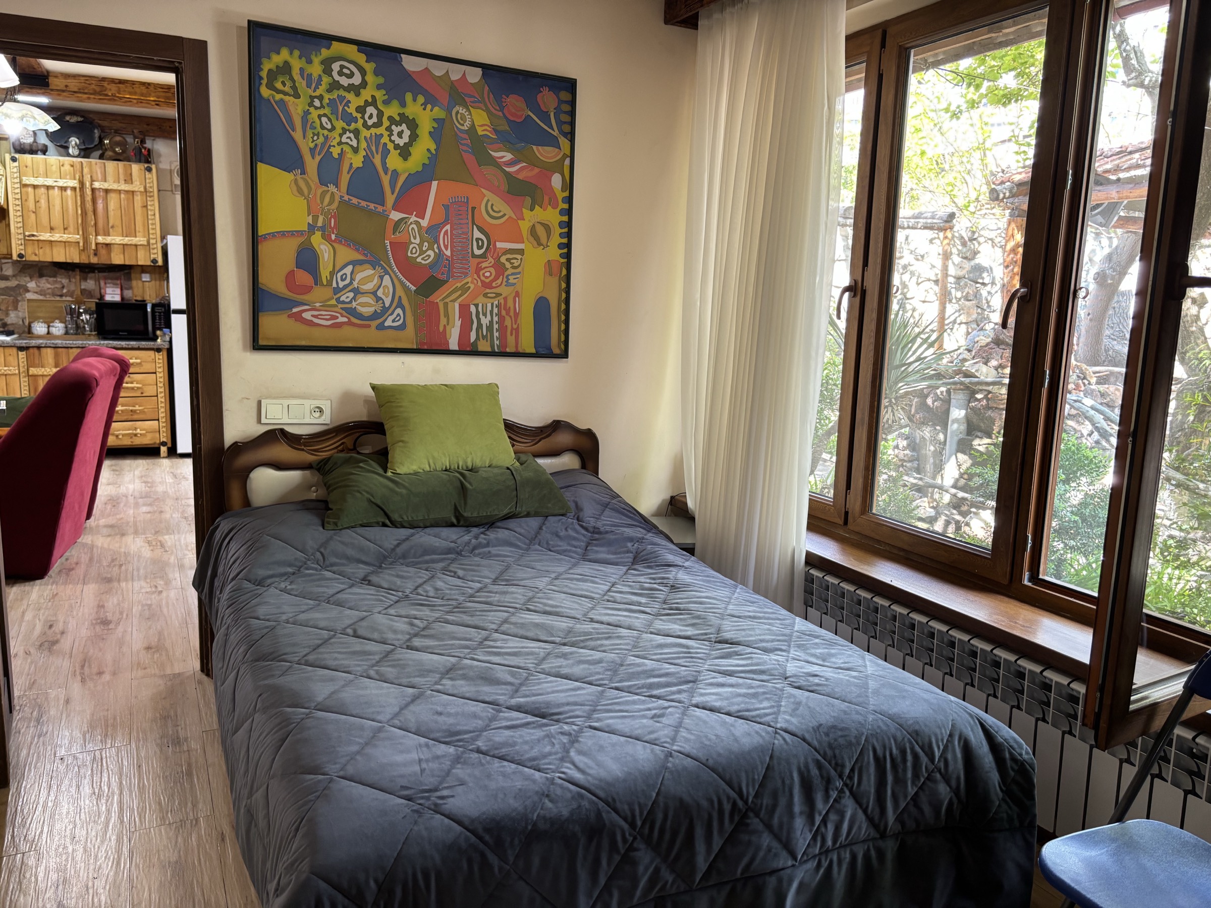 The first bedroom at Villa Nors, with a large canvas above the bed and a timber window onto the courtyard