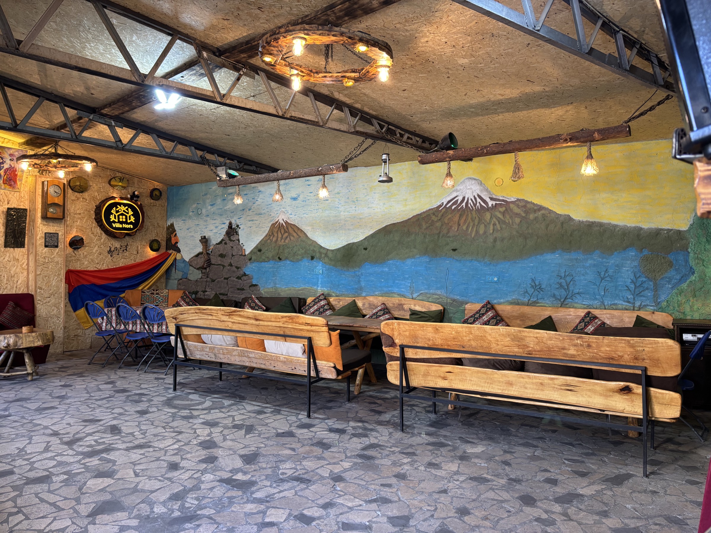 The mural hall with wooden benches and the Villa Nors sign