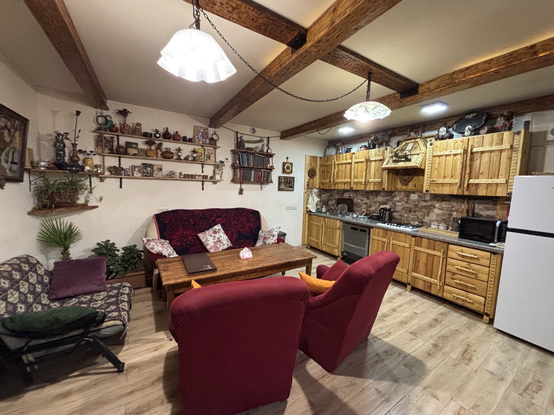 The living room and kitchen in one space, with wooden beams and sofas that open into beds